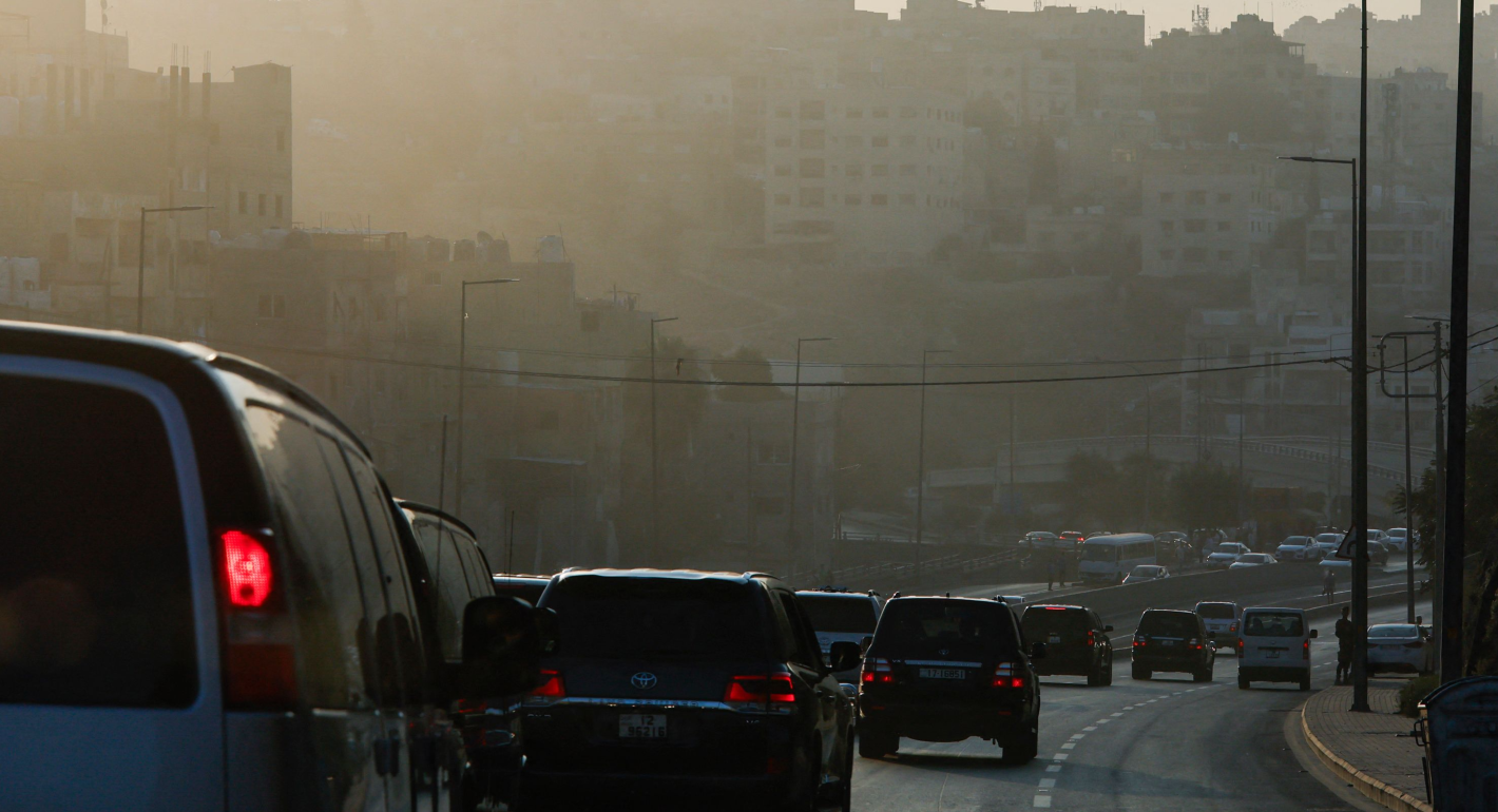 Line of cars drive through Amman surrounded by fog/smog